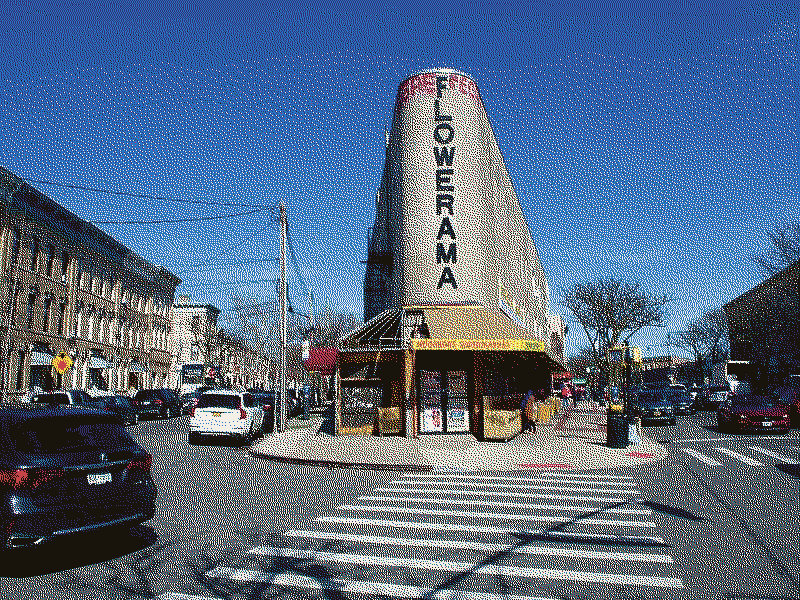 A flatiron-shaped building with a flowershop&rsquo;s name written down its face.